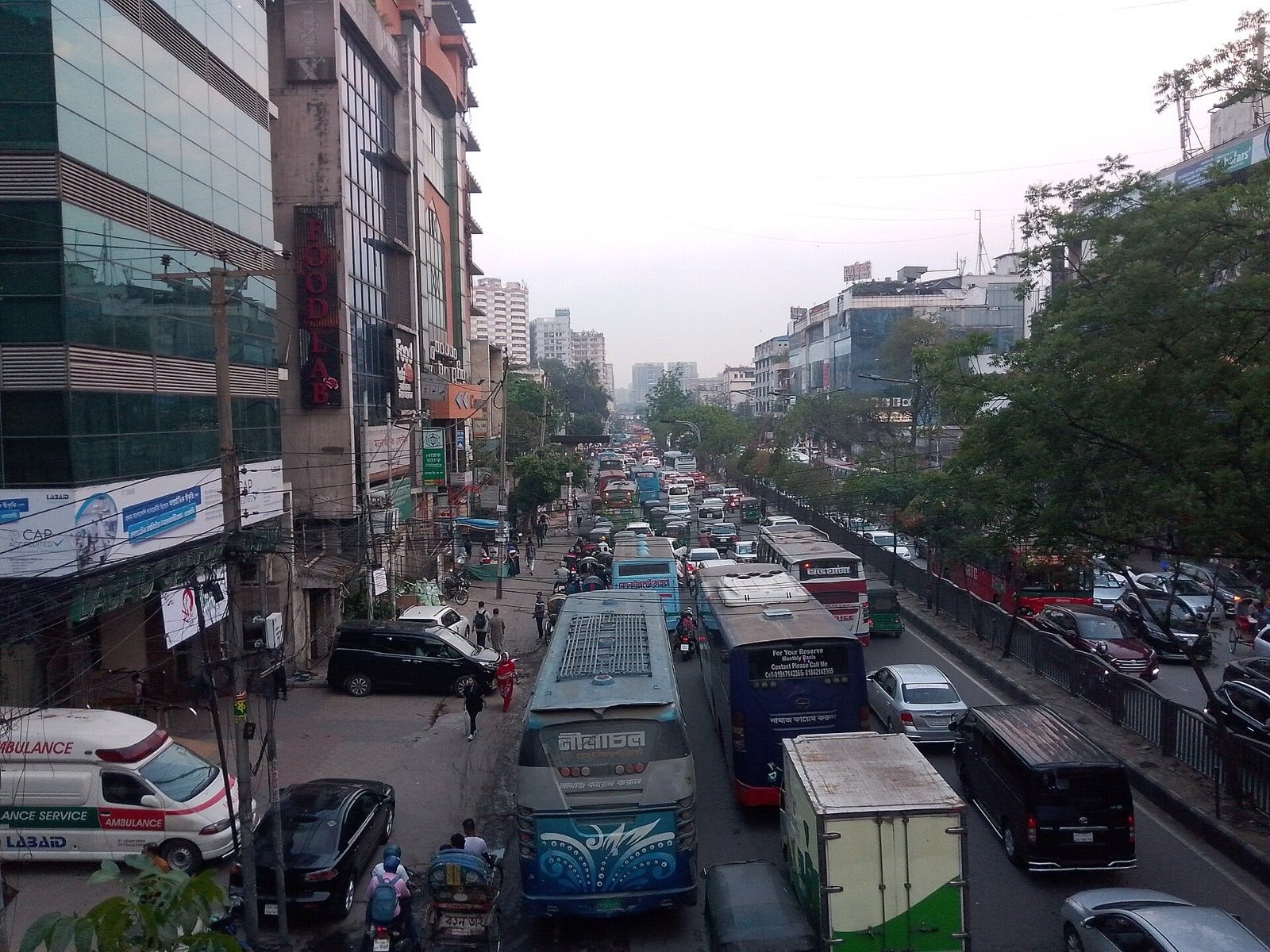 Gridlocked buses, cars and rickshaws on Mirpur Road in Dhaka, Bangladesh, with the skyline fading into haze